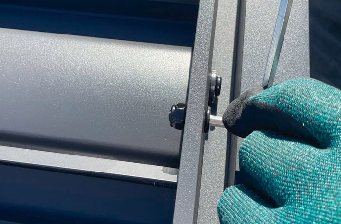 Person securing louvres on a gazebo with a hex key.