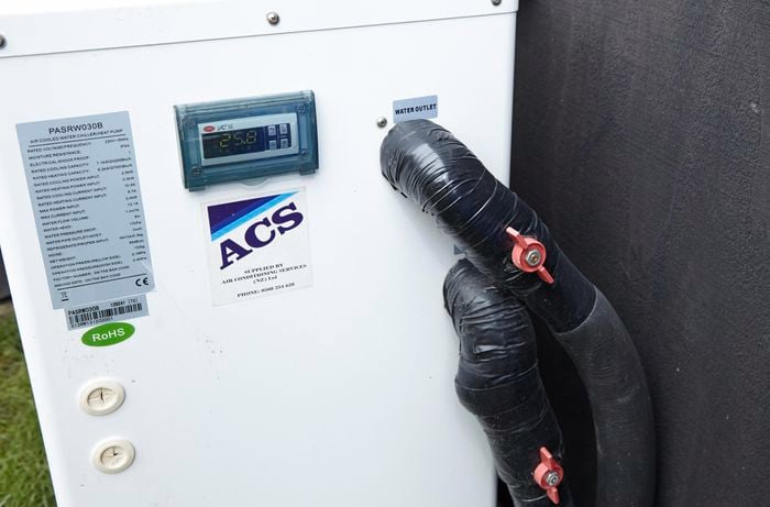 Closeup of a central air conditioning unit installed outside a house. The temperature reads 25.8 degrees.