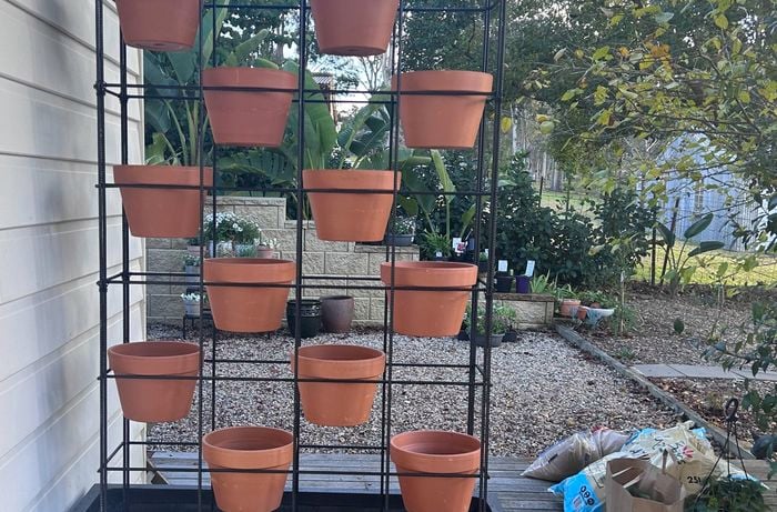 An empty vertical vegetable planter with pots added.