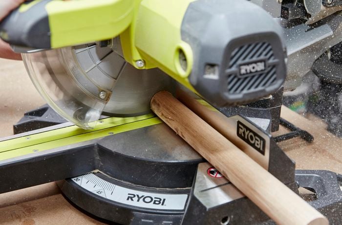 Person cutting timber dowel with circular saw.