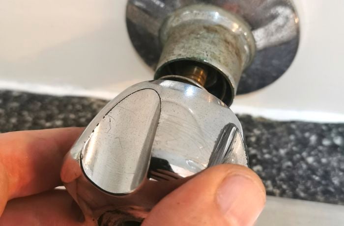 A hand screwing a tap handle into its place.