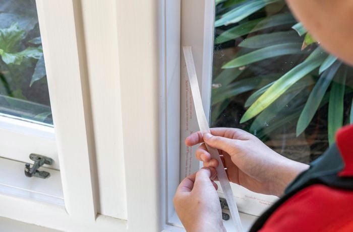 A Bunnings Team Member holding a piece of film next to a window