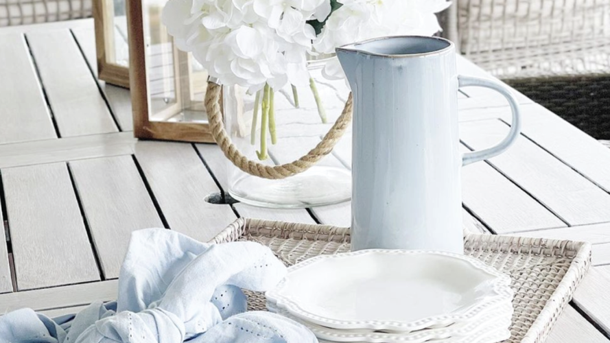 Table with jug, plates and napkins on tray along with showpieces. 