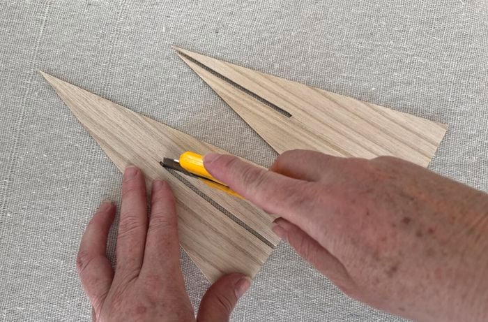 Hands use utility knife to cut strips in paper