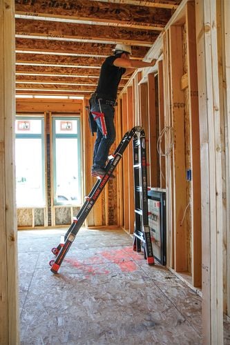 Person on adjustable A-frame ladder working on timber wall frame