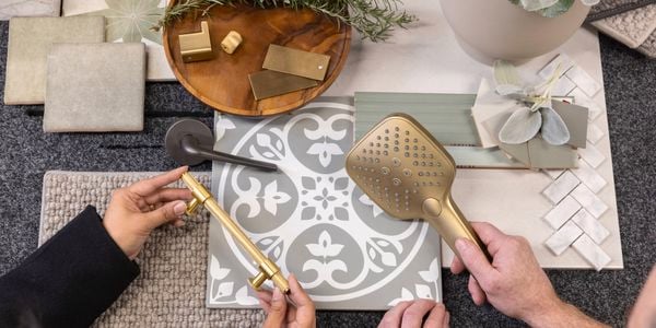 Two people holding kitchen products on a wooden table, with placemat and coasters.