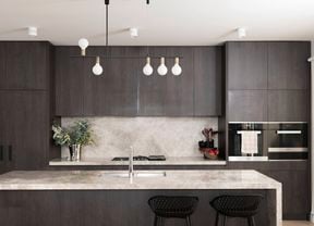 An image of a clean and organised kitchen featuring plenty of storage and a beautiful pendant light.