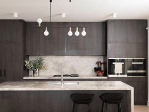 An image of a clean and organised kitchen featuring plenty of storage and a beautiful pendant light.