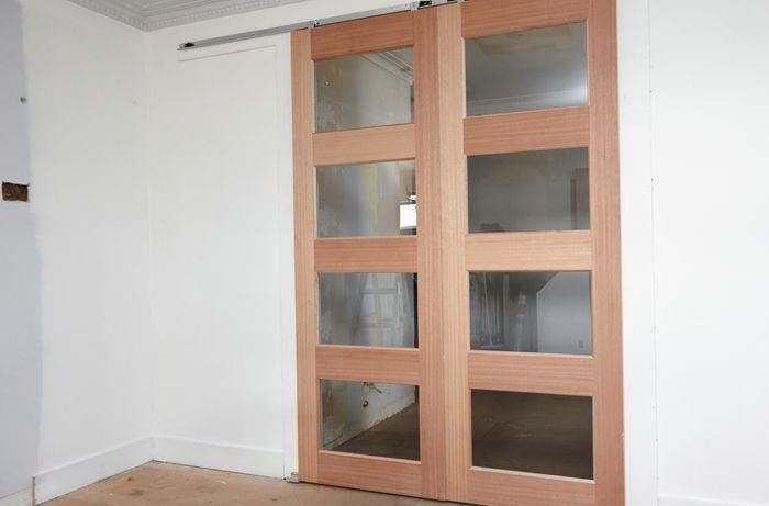 Installed wooden framed sliding doors with glass panels on a white wall