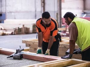 Two Bunnings team members assembling a building frame with nail guns