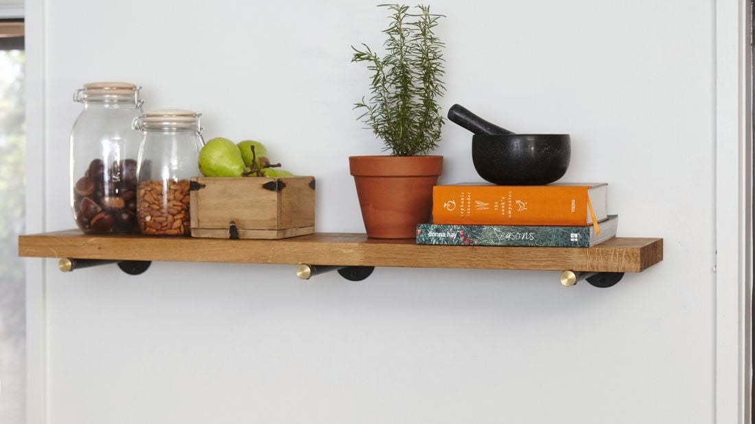 A timber kitchen shelf with jars of food and cookbooks