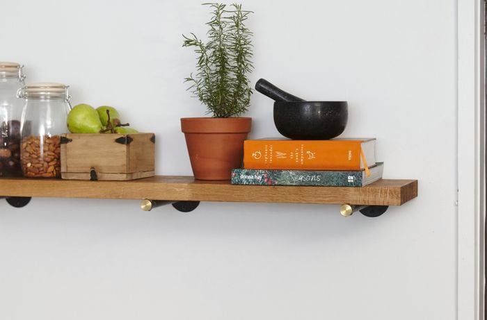 A timber kitchen shelf with jars of food and cookbooks