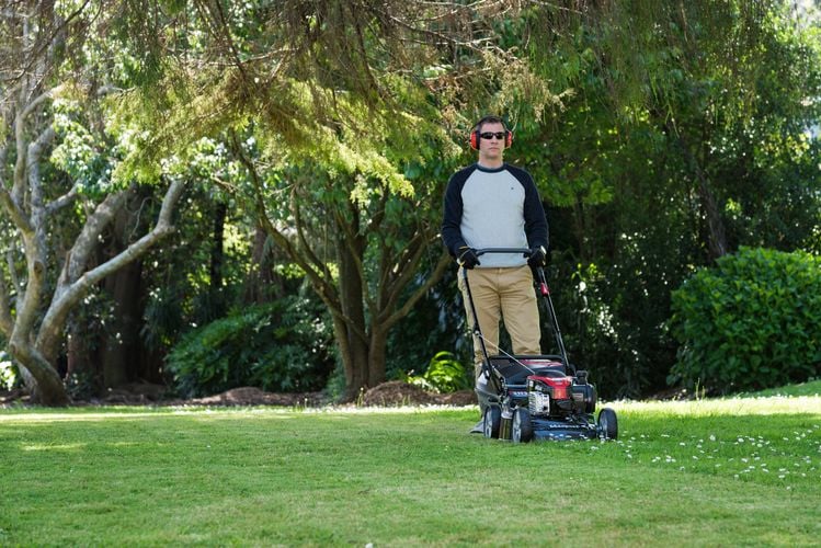 Person mowing lawn in backyard with cordless lawnmower