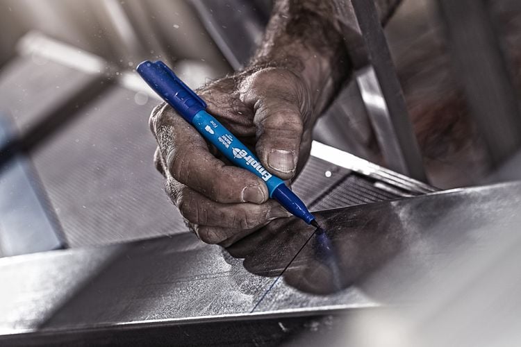 A piece of steel being marked with a felt tip marker