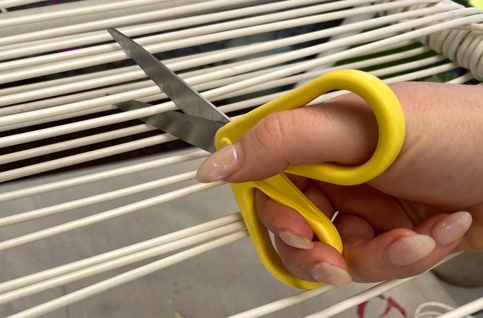 Get started on your D.I.Y. patio chair repair by cutting away the old cord from your damaged chair.