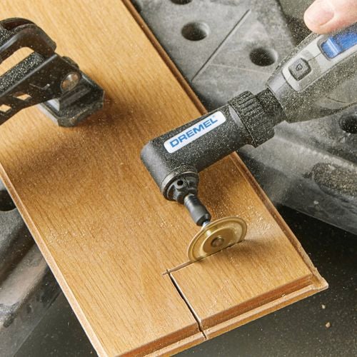 dremel tool cutting a wooden panel with a rotary blade.