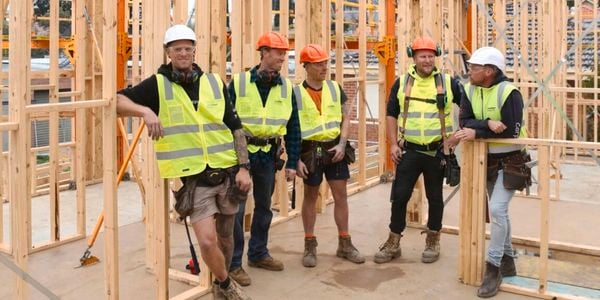 5 tradies wearing hard hats and high res vest on a work site