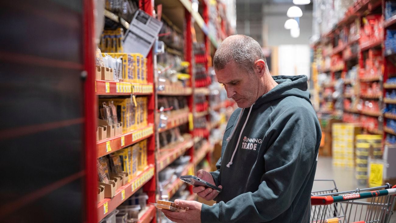 A Bunnings Trade customer uses the Bunnings Trade PowerPass app on his phone to scan a product in store