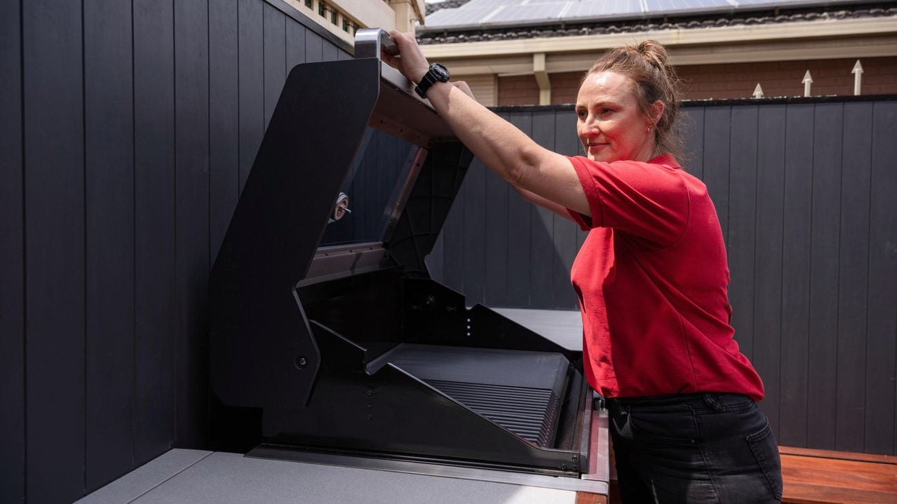 A woman opening a BBQ machine.