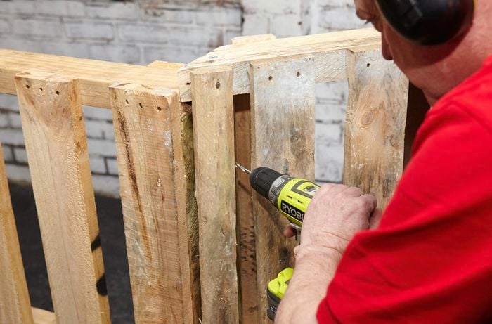 Two ends of a pallet cut in half and being drilled into by a Bunnings team member