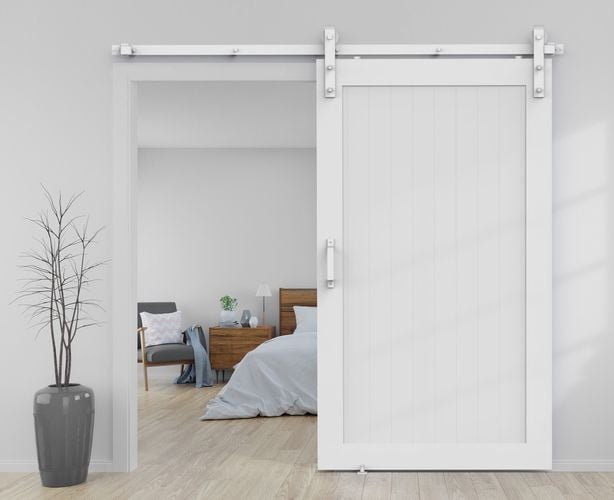 Bedroom interior featuring Rolltrak Matte White Side Mount Barn Door Track, Matte White Square Raised Handle, and Matte White Barn Door Floor Guide.