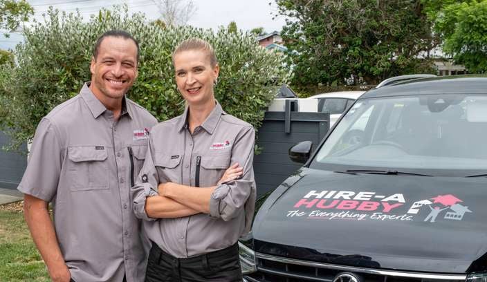 a man and woman standing in front of a hire a hubby van 