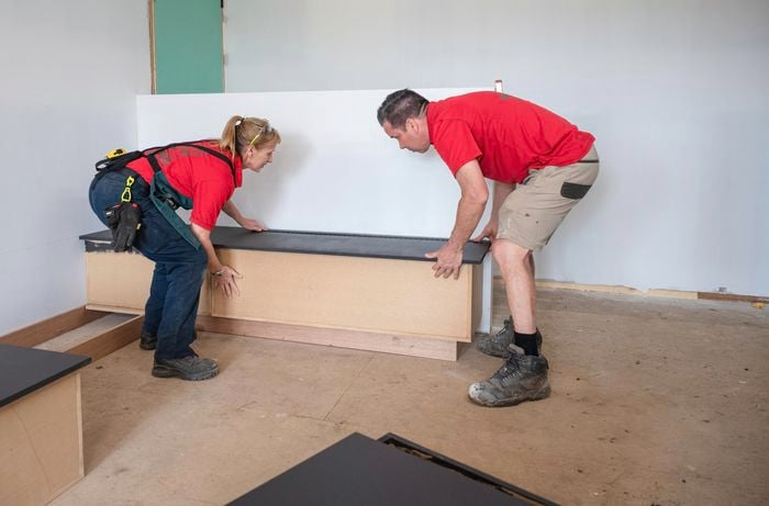 Two persons sitting the bench seat on top of the kickboards.