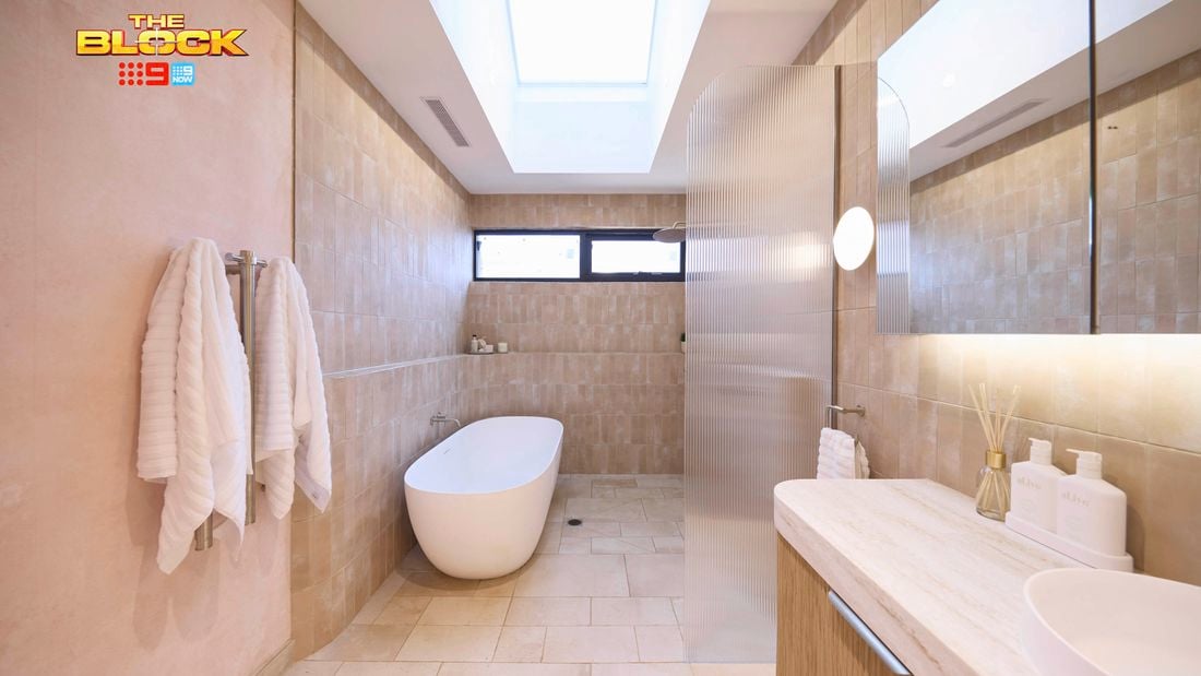 Natural coloured bathroom with a timber fluted profile vanity and marble benchtop and bath