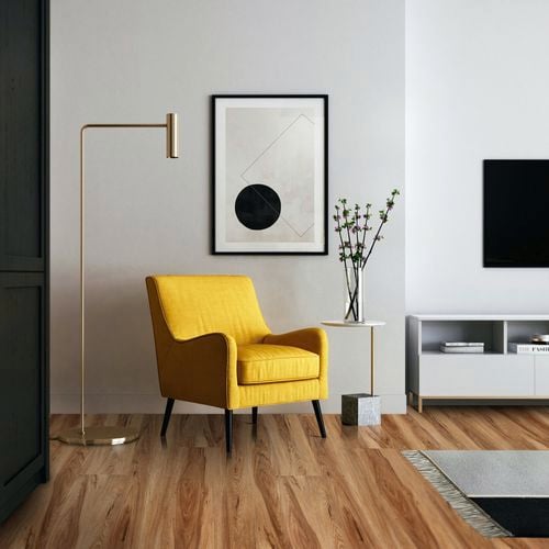 Modern living space with yellow occasional chair, gold floor lamp, wall print, side table on timber look floorboards.