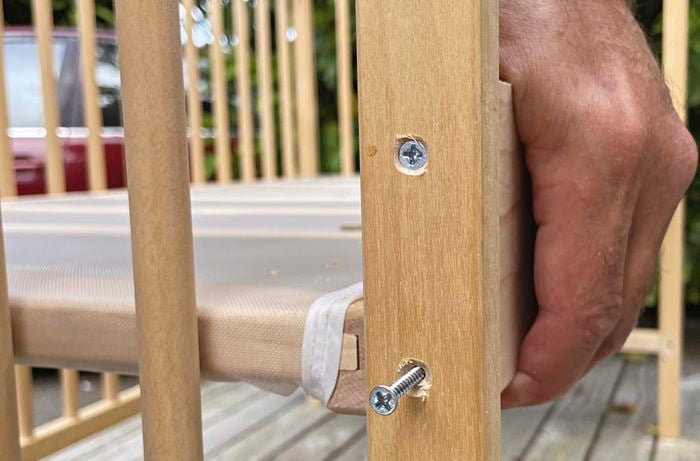 Hand joining two pieces of timber together with nails to form base of couch