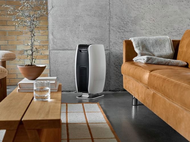 Air purifier in a living area near a tan colour couch.