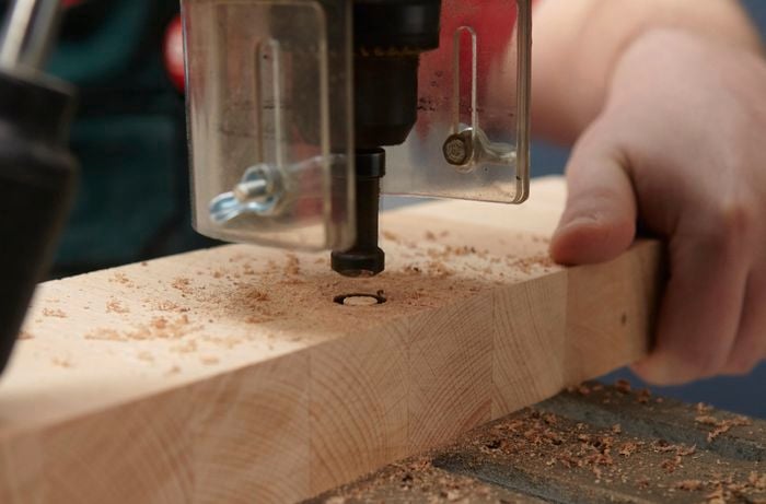 Person using plug cutter on bit of timber.
