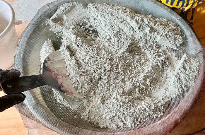 Cement, sand and oxide mixed in an old basin lined with insect mesh
