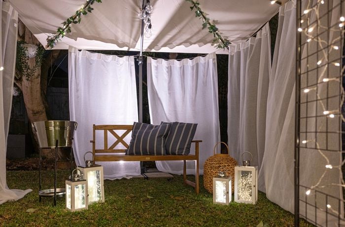 outdoor garden arch with fairy lights, bench timber chair with blue and white cushions