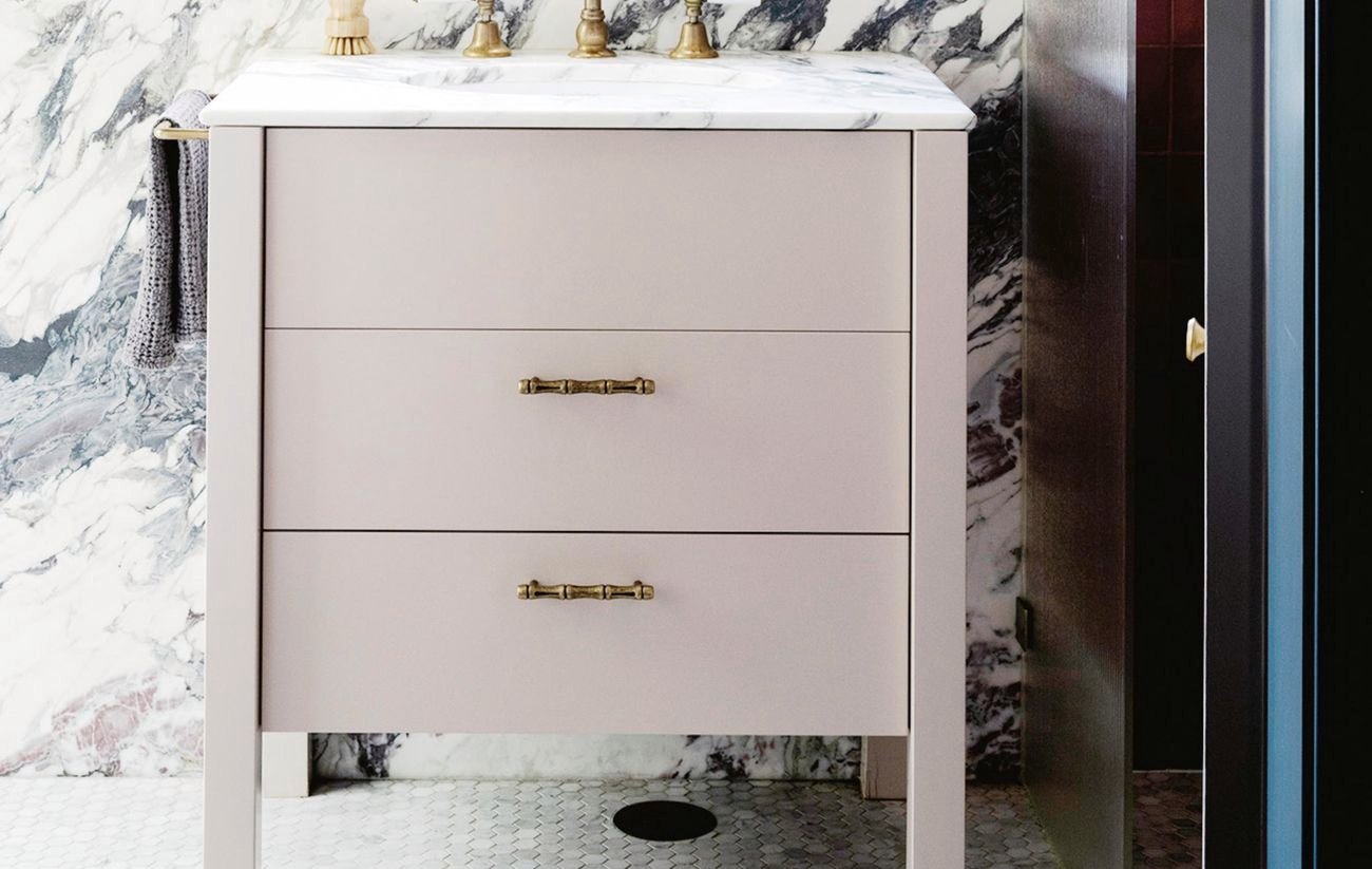 Pink vanity sits in front of window with blue trim