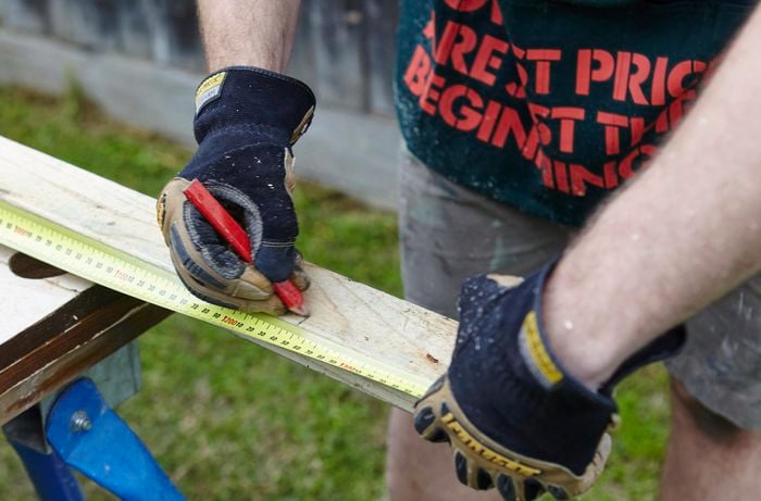A length of timber being measured and marked for later cutting with a pencil and tape measure