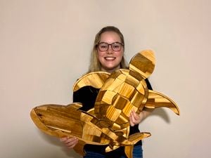 Alicia Clarke holding her woodwork designs.
