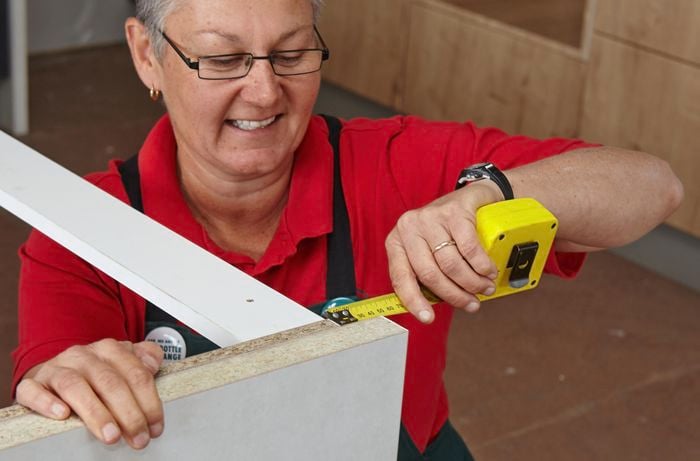 Person using measuring tape to measure cabinet