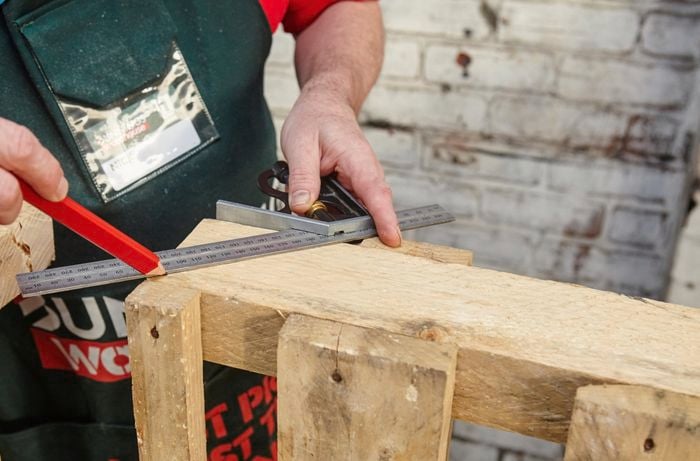 A Bunnings team member marking a wooden pallet with a pencil for making an angled cut into one side