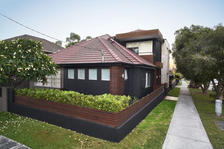 Exterior of renovated older house with extension, all painted charcoal with contrasting decking timber