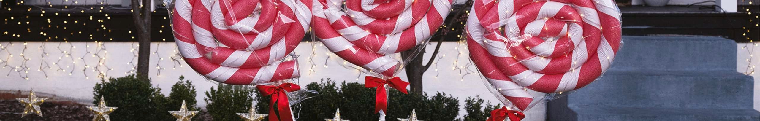  lollipops made from swimming noodles shaped to resemble Christmas in front yard