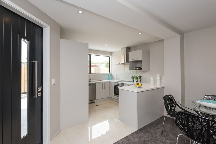 Modern white kitchen and living area and dark grey front door with glass panel