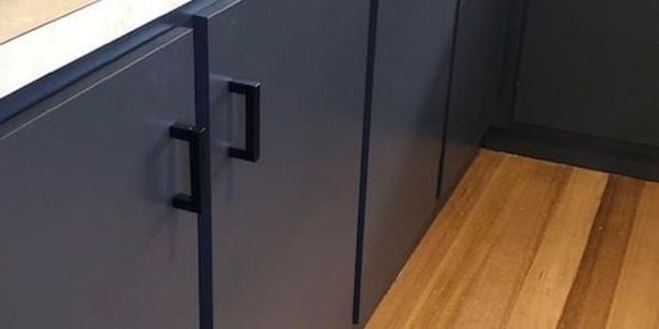 A kitchen with black cabinet doors and wooden floor