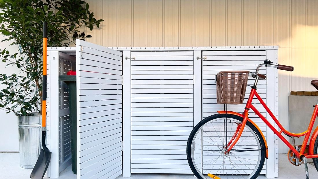 Three door bin screen with shovel in front of half-opened one bin screen and bicycle on other side. 