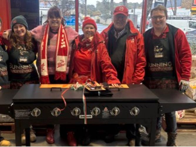 People and Bunnings Team Member's standing behind a Barbecue.