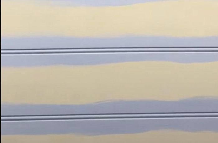 Pastel purple paint in horizontal lines over grooves on wall.