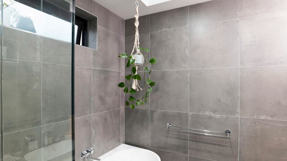 A potted plant in a macrame hanger in a bathroom