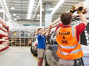 Trade Load & Go -team member helping customer load timber onto a car roof rack in a Bunnings timber yard