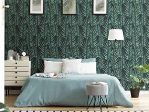 A bedroom with a bed and green wallpaper with leaves.