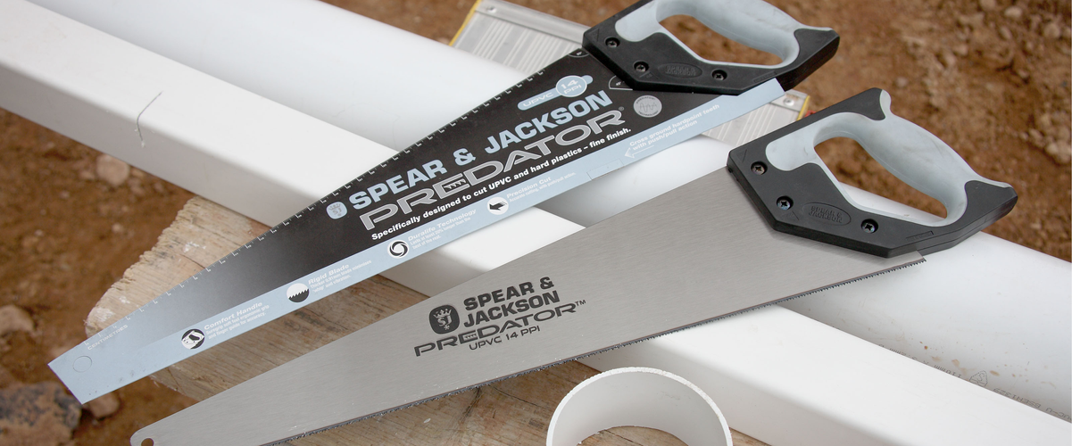 Two hand saws resting on PVC pipes that have been partly sawn through